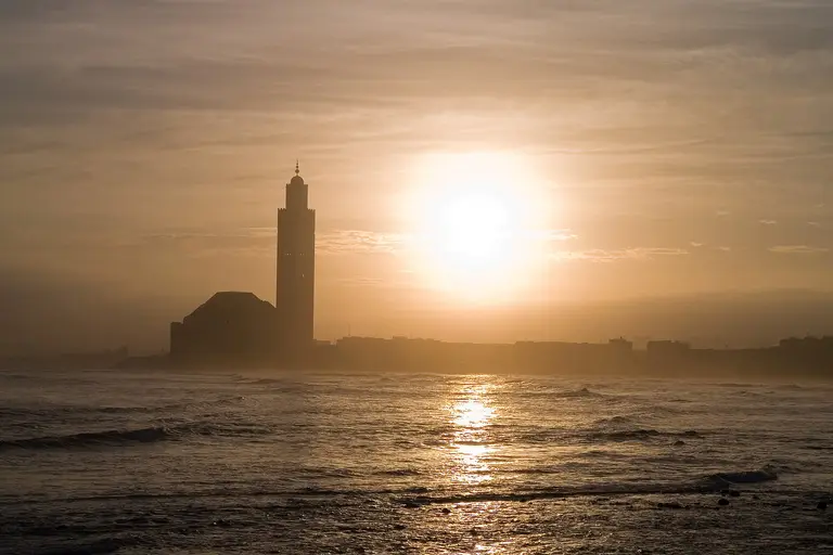 La mosquée Hassan II de Casablanca en contre-jour face au soleil couchant sur l’Atlantique