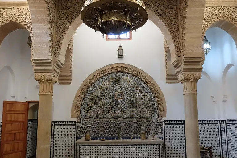 The restored Saffarin hammam in Fez, with a zellige fountain, carved arches and a brass lantern